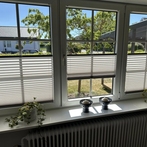 Hvide plissé gardiner i stuevindue